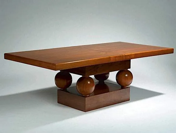 René HERBST (1891-1982) Table de milieu en noyer à plateau rectangulaire et épaisse ceinture sur piétement à support de plateau en retrait reposant sur quatre boules à attaches cylindriques et talon rectangulaire. Adjugé à 49 568 €