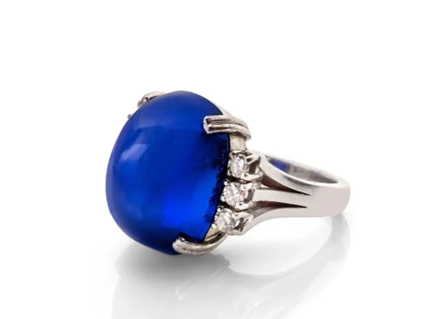 BAGUE En or gris 18k (750), ornée d'un saphir du Cachemire "Royal Blue" taillé en cabochon entre six diamants taillés en brillant Poids du saphir : 22,80 ct